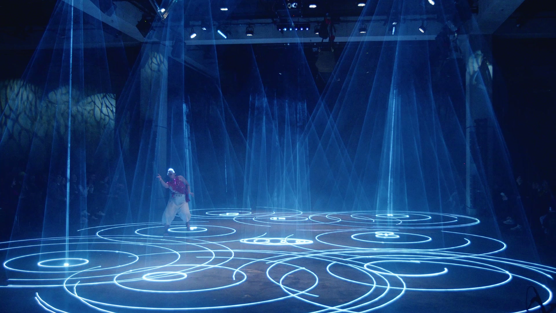 Performer moving across an illuminated field of circular drawings in Tate Modern’s Tanks